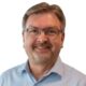 Verein Wiga Digital Dieter Hofer: Porträt eines freundlich lächelnden Mannes mit Brille und hellem Hemd vor schwarzem Hintergrund. Das Bild zeigt Dieter Hofer als erfahrenen Mentor und Digitalisierungsexperten mit sympathischer und professioneller Ausstrahlung.