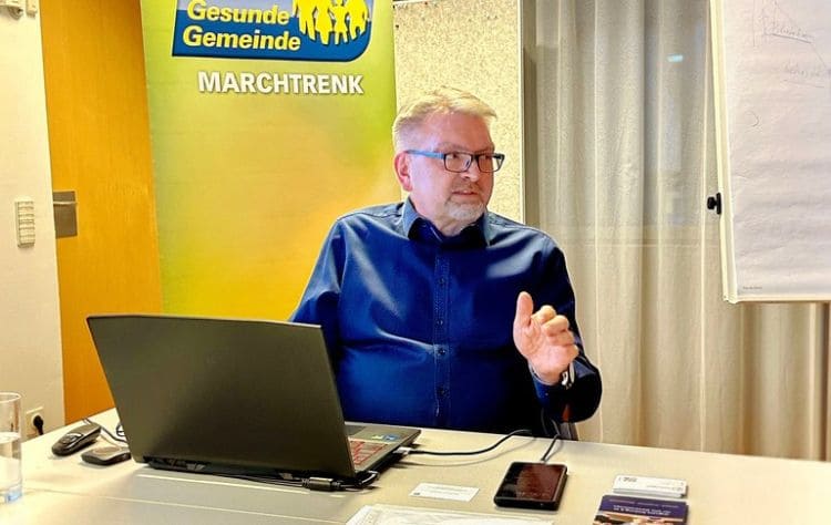 Dieter Hofer, Obmann von WIGA Digital, erklärt beim Workshop „Digital gesund – KI im Gesundheitsalltag“ im Stadtamt Marchtrenk den praktischen Einsatz künstlicher Intelligenz im Gesundheitsbereich. Er sitzt mit einem Laptop am Tisch und erläutert, wie KI helfen kann, medizinische Befunde und Gesundheitsinformationen besser zu verstehen. Im Hintergrund ist das Logo „Gesunde Gemeinde Marchtrenk“ zu sehen.